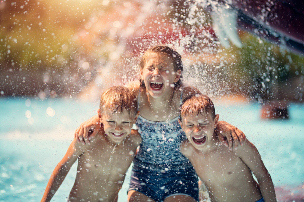 Kids having fun in pool in a waterpark. Laughing and screaming after being splashed with bucket of cold water.