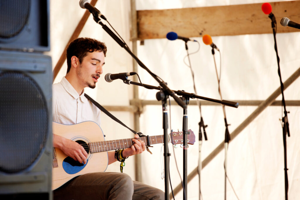 A guitarist playing and singing at a live folk festival, Castlewood Wine Festival, Devon