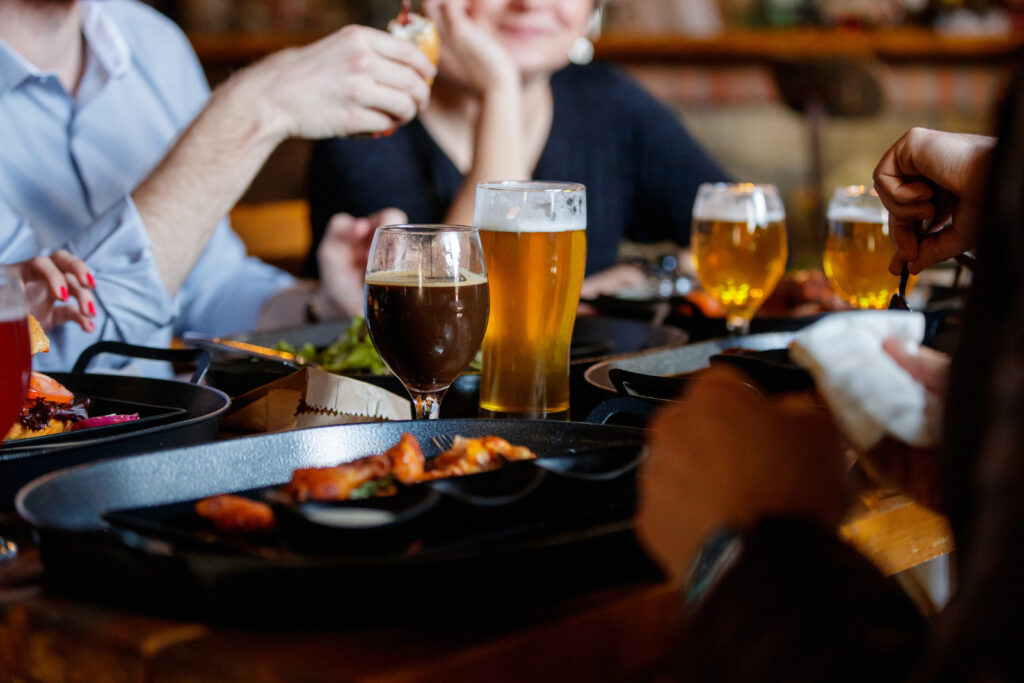 Friends sitting at the table in a pub and enjoying dinner and craft beer after work