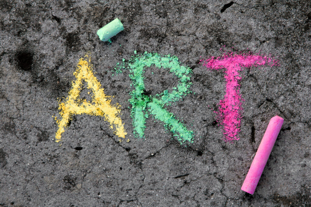 Colorful chalk drawing on sidewalk: Word ART and pieces of chalk