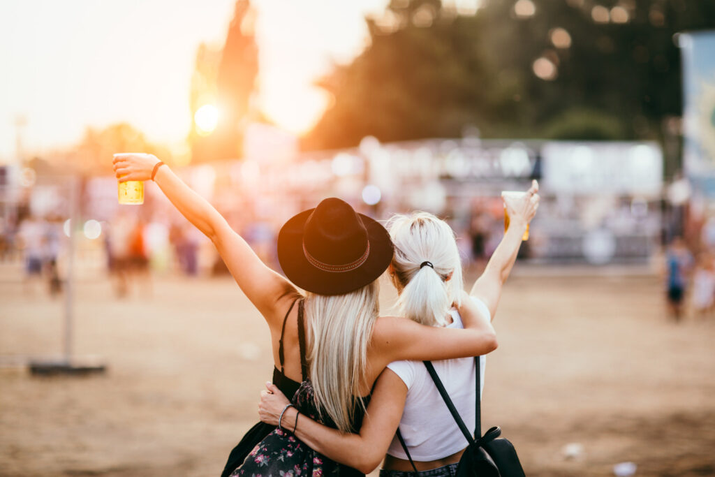 Friends drinking beer and having fun at music festival. Back view