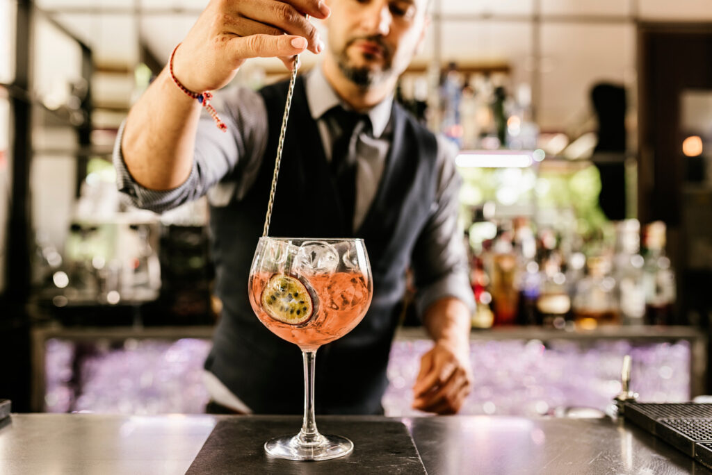 Expert barman is making cocktail at night club.